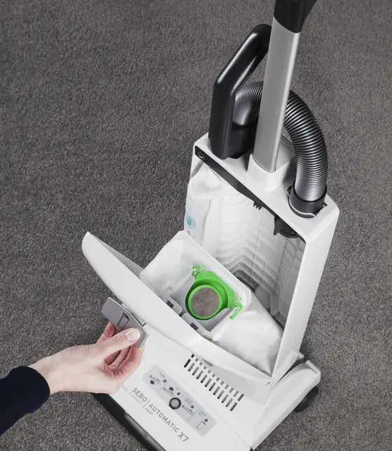 Genuine SEBO filter bag fitted in an AUTOMATIC X7, with the front cover open to show the green sealing collar; vacuum shown for fitment only